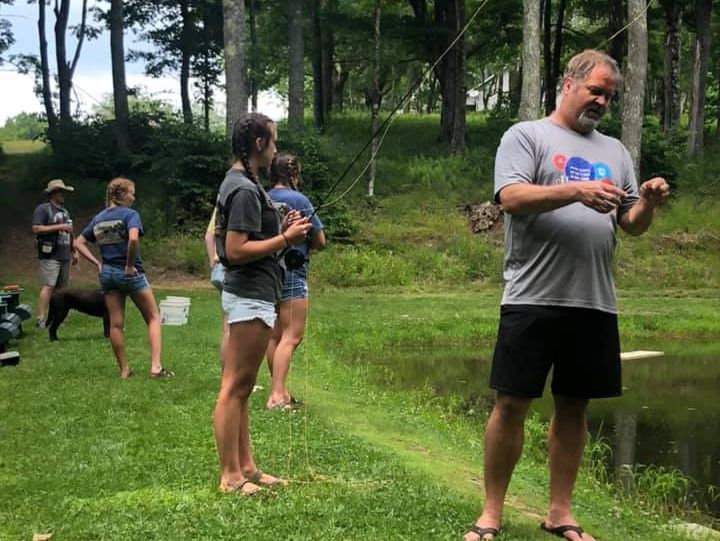 Picture of Delegate Riley fishing at a WV Pond with his children: McKinnley and Avery Riley and their neighbors, Duane Boyce and his daughter Hailey.  Riley family dog, Baily is in the background.
